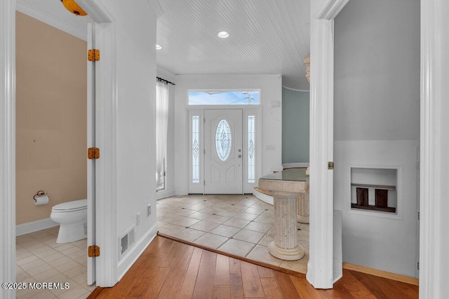 entryway featuring ornamental molding, visible vents, baseboards, and hardwood / wood-style flooring