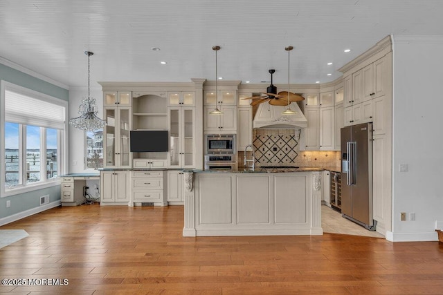 kitchen with crown molding, backsplash, appliances with stainless steel finishes, light wood-style floors, and a sink