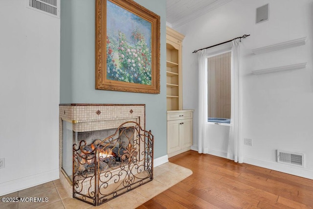 interior space with baseboards, visible vents, wood finished floors, and a multi sided fireplace