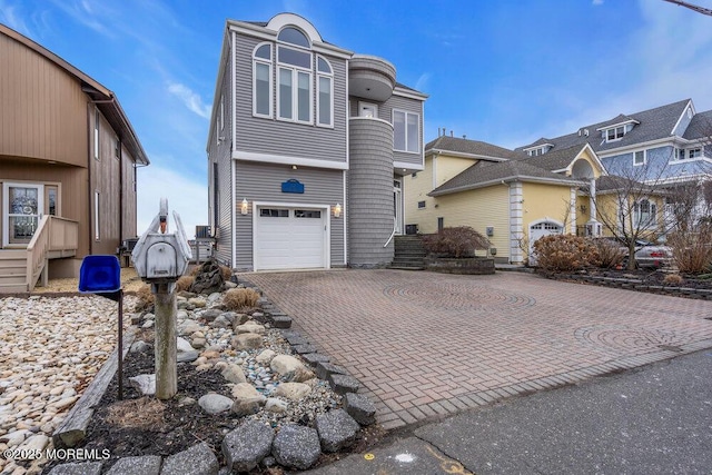 view of front facade with an attached garage, a balcony, and decorative driveway