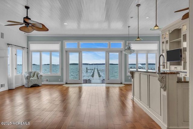 interior space featuring a ceiling fan, visible vents, plenty of natural light, and a water view