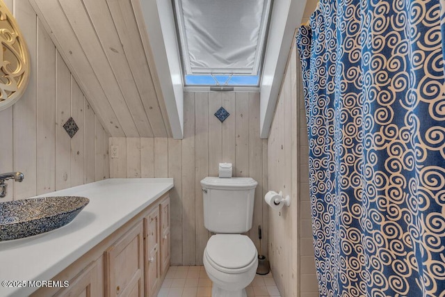 bathroom featuring wood walls, tile patterned flooring, vanity, and toilet