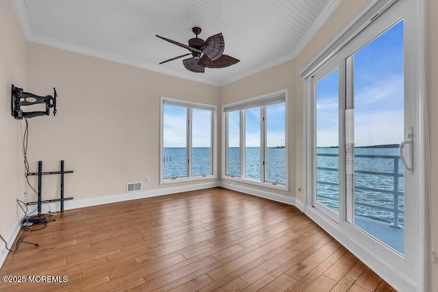 empty room with a water view, wood finished floors, visible vents, and crown molding