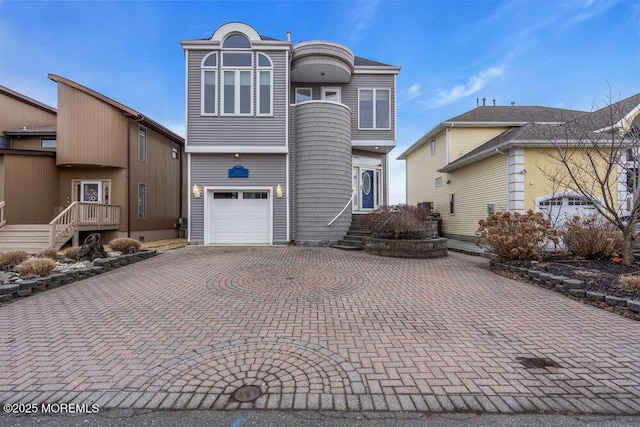 view of front of property with a balcony, an attached garage, and decorative driveway