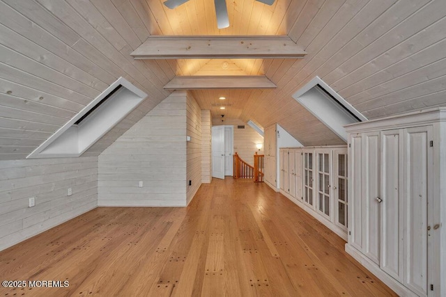 bonus room featuring vaulted ceiling with skylight, wood walls, wood ceiling, a ceiling fan, and hardwood / wood-style floors