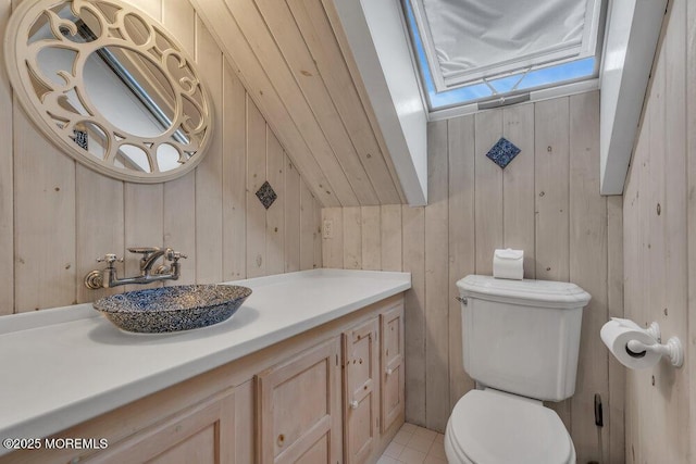 bathroom with vanity, toilet, and wooden walls