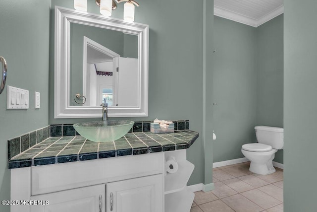 bathroom with tile patterned flooring, toilet, vanity, baseboards, and ornamental molding