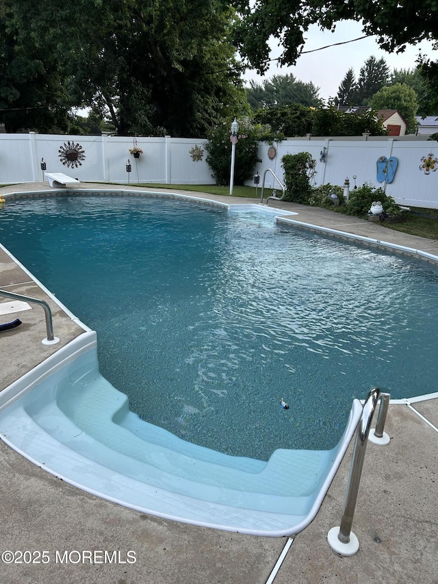 view of swimming pool with a diving board, a fenced backyard, and a fenced in pool