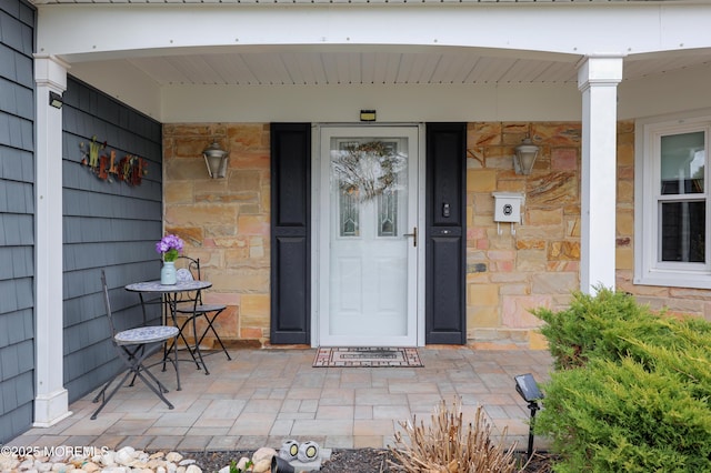 entrance to property with a porch and stone siding