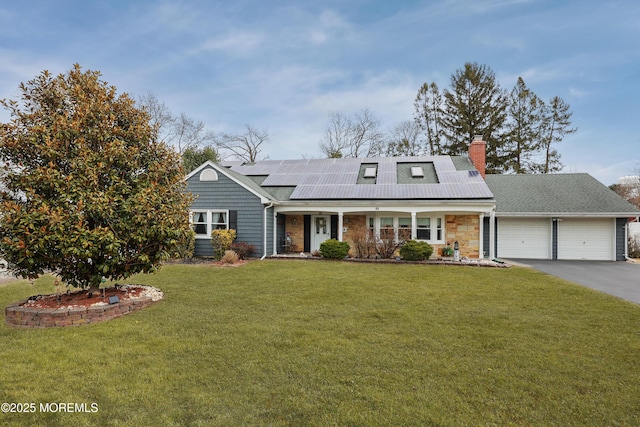 view of front of home with covered porch, a front yard, roof mounted solar panels, a garage, and driveway