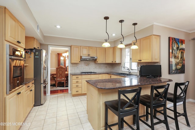 kitchen featuring tasteful backsplash, a peninsula, stainless steel appliances, light brown cabinetry, and a sink