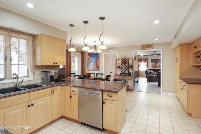 kitchen featuring backsplash, stainless steel dishwasher, light brown cabinets, a sink, and a peninsula