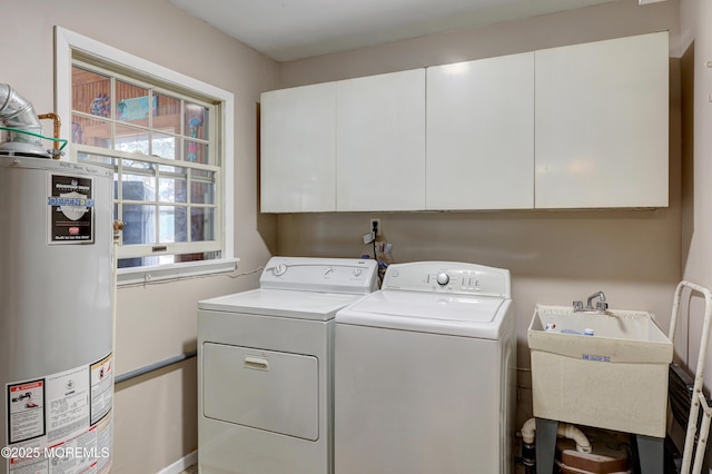 clothes washing area with cabinet space, washing machine and dryer, water heater, and a sink