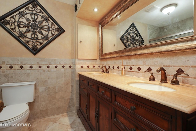 bathroom featuring a sink, tile walls, toilet, and tile patterned floors