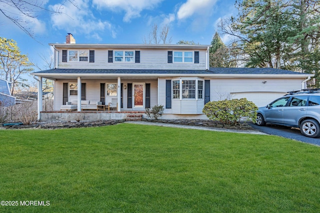 view of front facade with a chimney, aphalt driveway, an attached garage, covered porch, and a front lawn