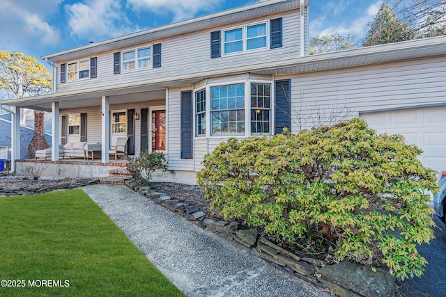 view of front facade featuring a porch, a front lawn, and a garage