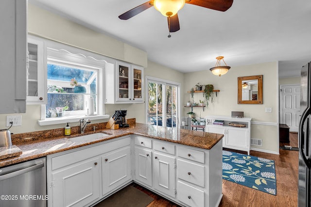 kitchen with stone countertops, white cabinets, dishwasher, dark wood-style flooring, and a peninsula