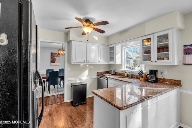 kitchen featuring dark wood-style floors, freestanding refrigerator, a sink, dishwasher, and a peninsula