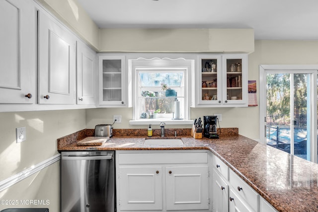 kitchen featuring dishwasher, glass insert cabinets, a sink, and white cabinetry