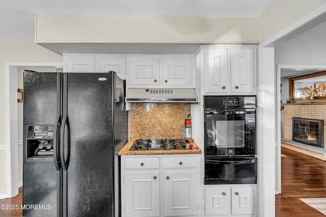 kitchen featuring black appliances, under cabinet range hood, dark wood finished floors, and a warming drawer