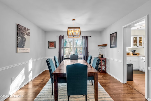 dining area featuring an inviting chandelier, baseboards, and dark wood-style flooring