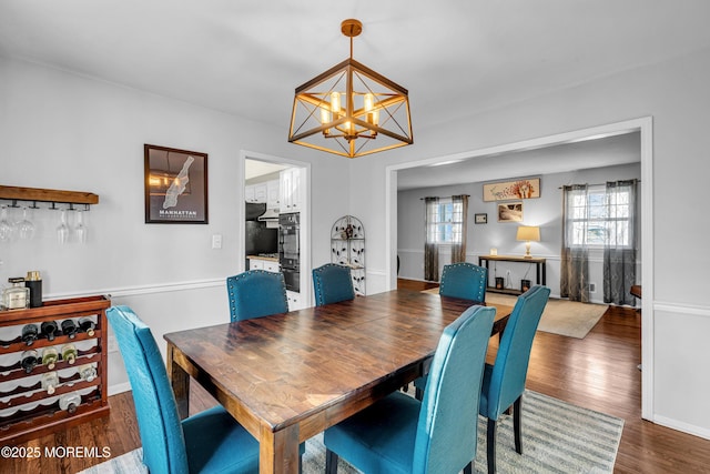 dining area featuring a dry bar, wood finished floors, and a notable chandelier