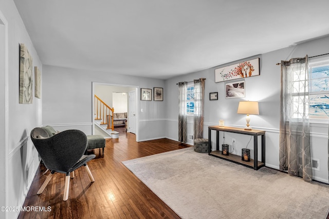 sitting room featuring visible vents, stairway, hardwood / wood-style flooring, and a healthy amount of sunlight