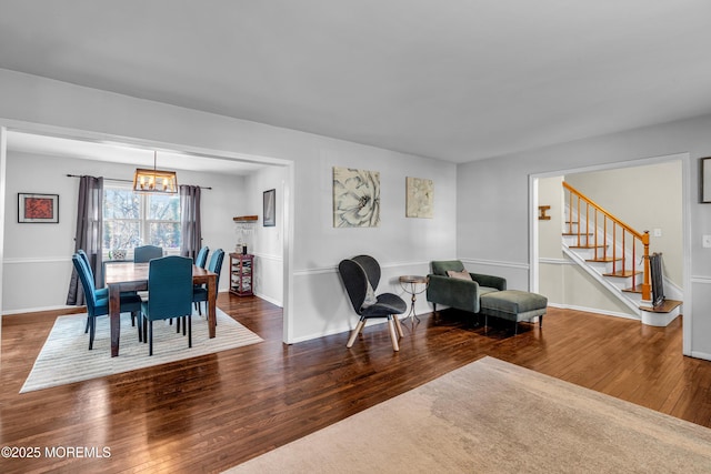 dining area featuring hardwood / wood-style flooring, stairs, baseboards, and a notable chandelier