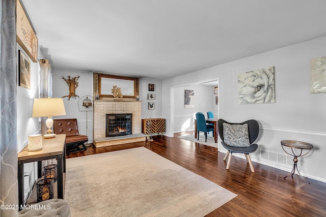 living area with a brick fireplace, baseboards, and wood finished floors