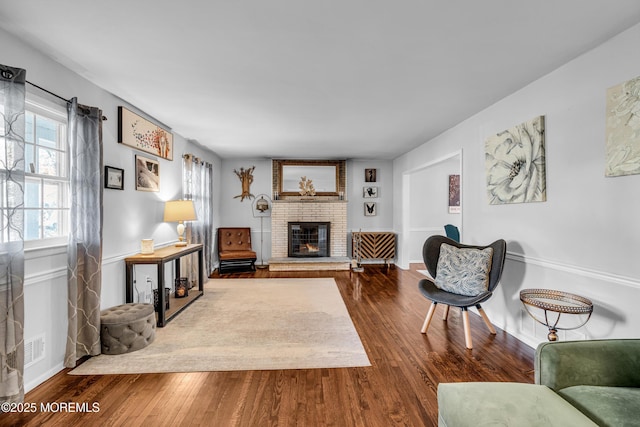 living area featuring a fireplace, dark wood finished floors, and baseboards