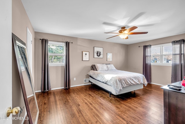 bedroom with a ceiling fan, visible vents, baseboards, and hardwood / wood-style flooring