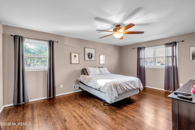 bedroom with ceiling fan, wood finished floors, visible vents, and baseboards