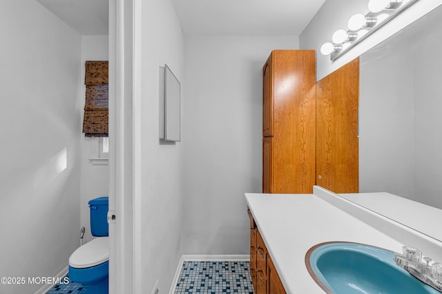 bathroom featuring toilet, vanity, and baseboards