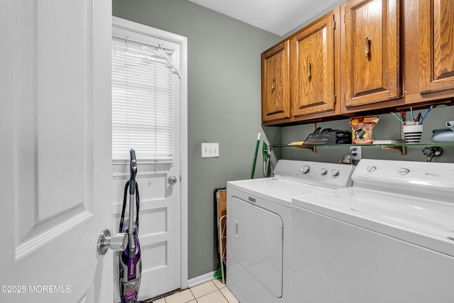 clothes washing area with light tile patterned floors, cabinet space, and washer and dryer