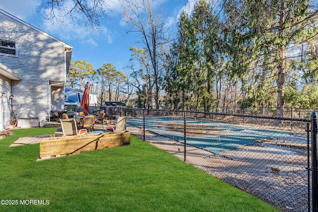 view of tennis court with a yard and fence