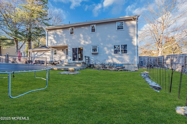 rear view of property featuring a trampoline, a fenced backyard, and a yard