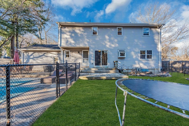 back of house featuring fence private yard, a trampoline, a fenced in pool, and a yard