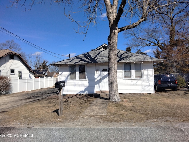 view of front facade with fence and roof with shingles