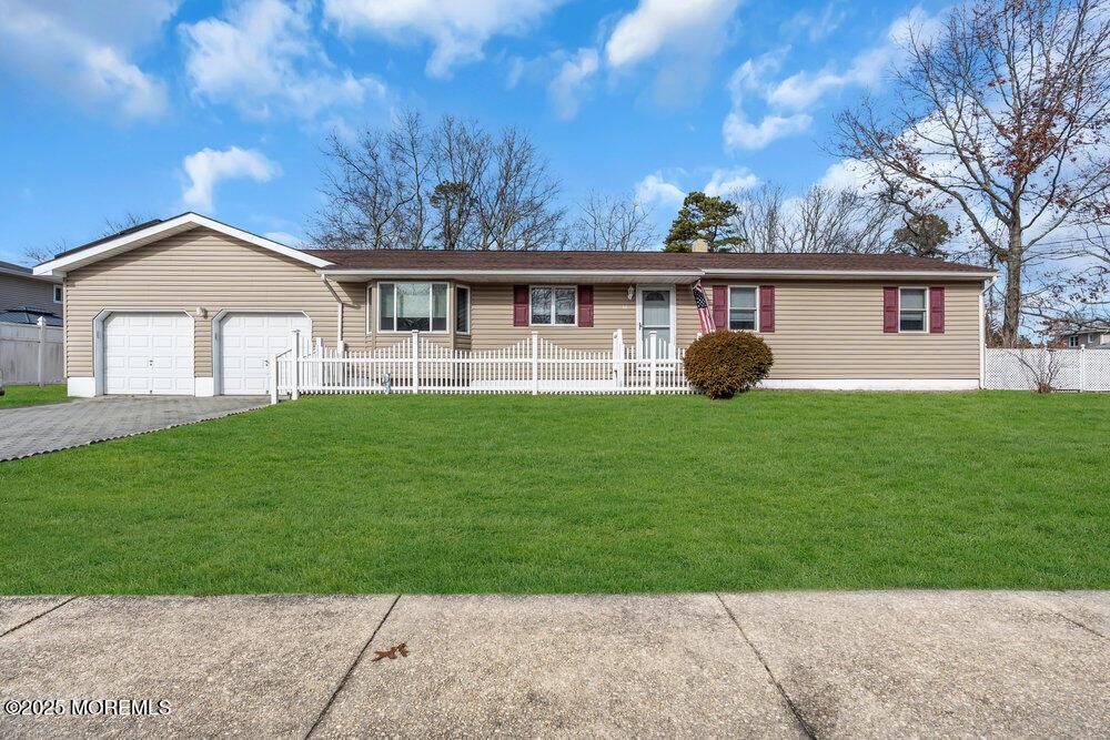 ranch-style house featuring aphalt driveway, an attached garage, a front yard, and a fenced front yard