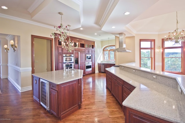 kitchen with an inviting chandelier, a large island, wine cooler, and exhaust hood