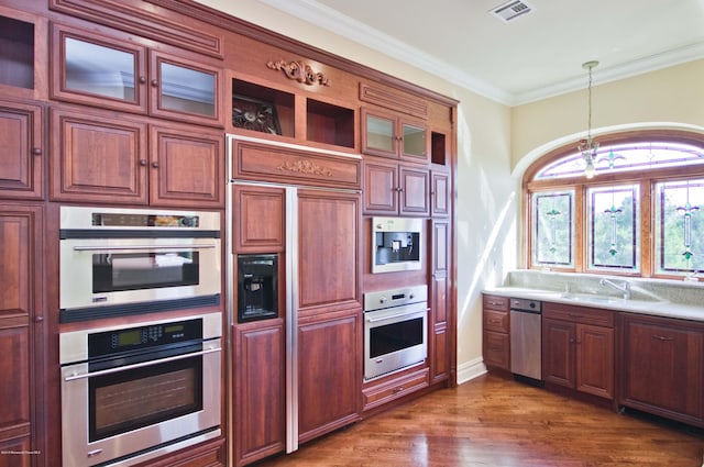 kitchen featuring visible vents, dark wood finished floors, ornamental molding, stainless steel double oven, and a sink