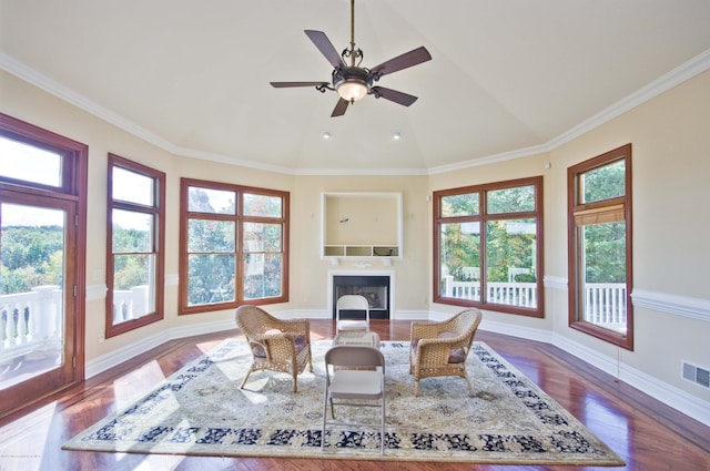 dining room with a fireplace, wood finished floors, baseboards, vaulted ceiling, and ornamental molding