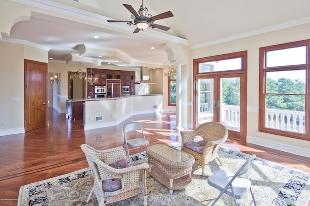 living area featuring crown molding, wood finished floors, visible vents, baseboards, and ornate columns