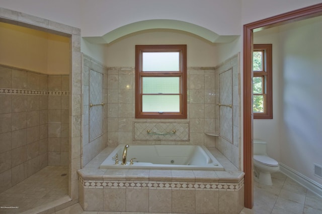 bathroom with toilet, a healthy amount of sunlight, tile patterned flooring, and a jetted tub