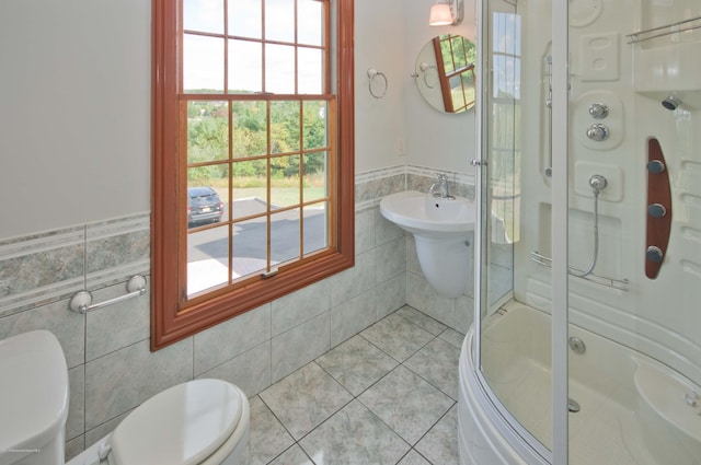 bathroom featuring tile walls, toilet, wainscoting, a shower stall, and tile patterned flooring