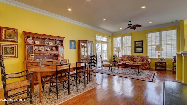 dining room featuring hardwood / wood-style floors, a ceiling fan, baseboards, and crown molding