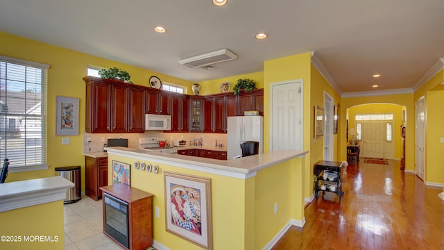 kitchen featuring reddish brown cabinets, white appliances, light countertops, and tasteful backsplash