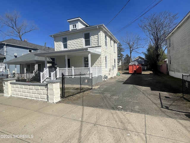 american foursquare style home featuring a fenced front yard, a porch, and driveway