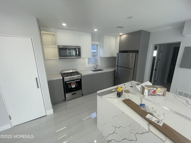 kitchen featuring electric panel, a sink, appliances with stainless steel finishes, modern cabinets, and backsplash