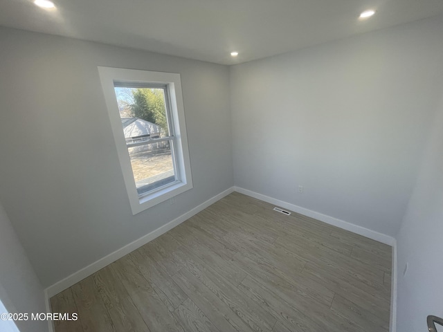 empty room with recessed lighting, visible vents, baseboards, and wood finished floors